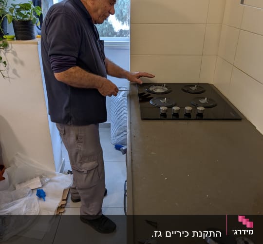 אדם מתקין כיריים גז עם כלים על השיש
